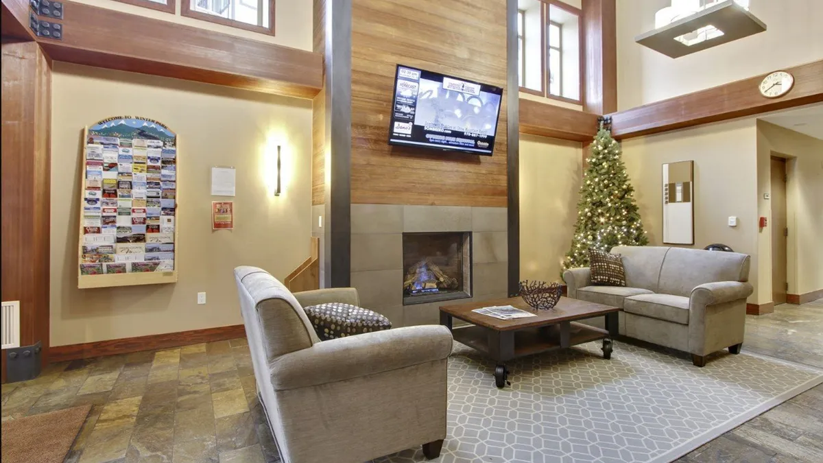A cozy lobby area featuring a grand fireplace, comfortable sofas, and a festive touch with a Christmas tree. The setting is warm and inviting, ideal for après-ski gatherings or relaxing after a day of adventure.