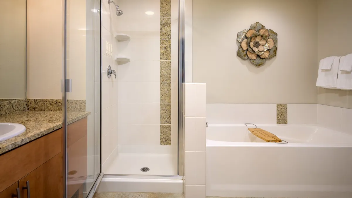 A tranquil, upscale bathroom with a glass shower enclosure, freestanding bathtub, granite countertop, and decorative wall art. The space is designed for relaxation and self-care, with a soothing, spa-like ambiance.